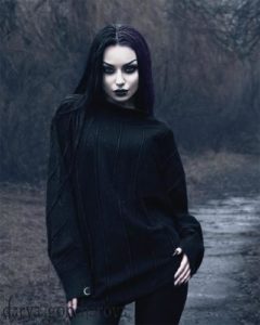 An image of a woman in black clothes with a pale face and dark make-up