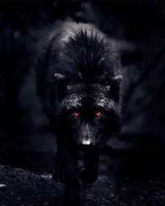 A giant black dog with red, glowing eyes against a dark, smoky background.