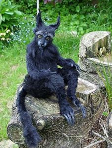 A black furry creature with pointy ears and a tail